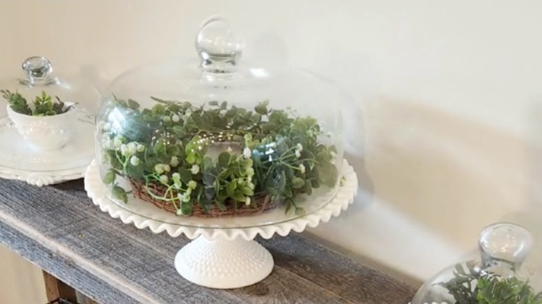 Milk glass cake stand with a greenery wreath on top