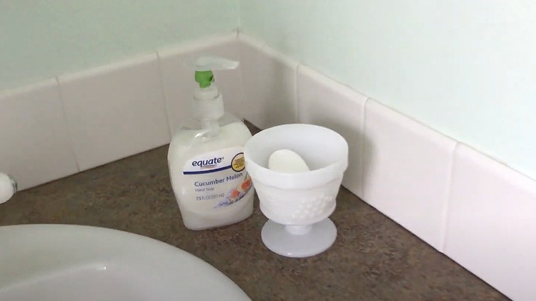 Soap bar inside a milk glass pedestal cup in a bathroom