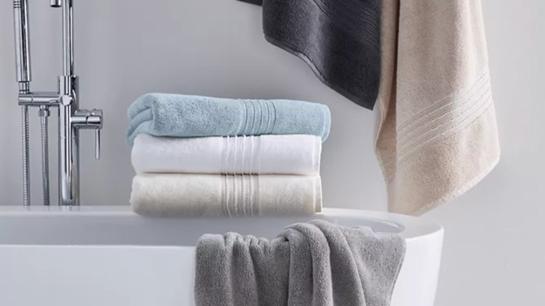 Macy's Hotel Collection turkish bath towels sitting folded on a tub and draped across a tub