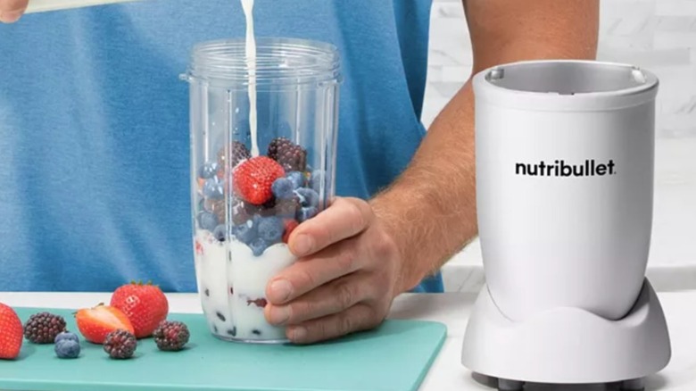 hands using NutriBullet to make a berry smoothie