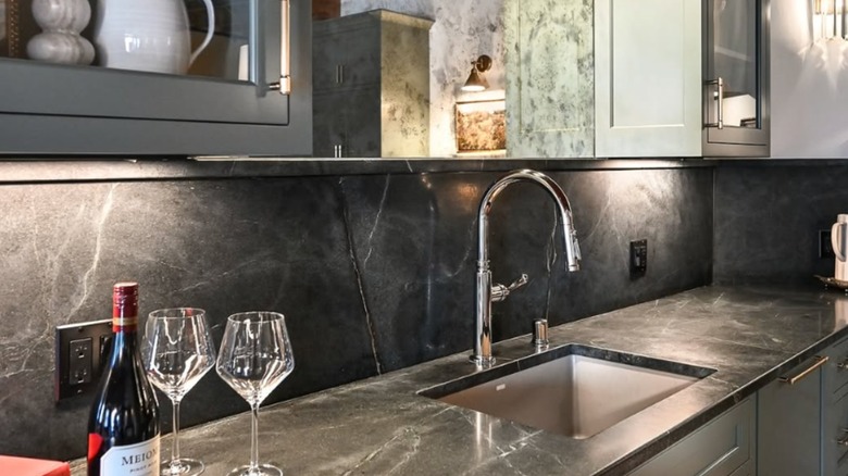 A soapstone backsplash with two glasses of wine on the counter
