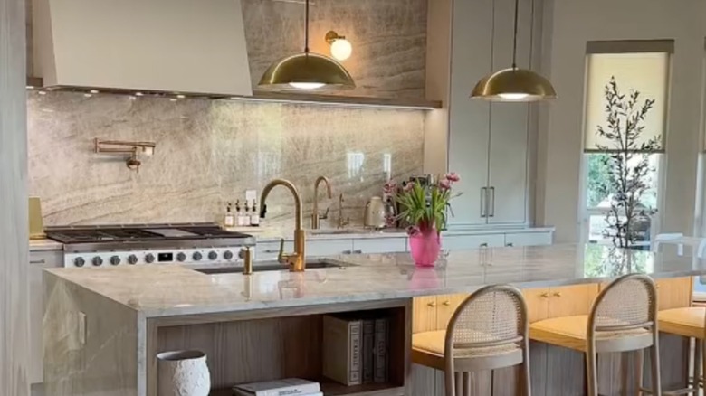 A Taj Mahal Quartzite kitchen with a slab backsplash and counter with stools