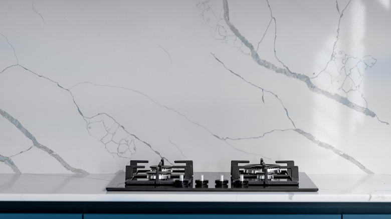 A white marble backsplash behind a stove