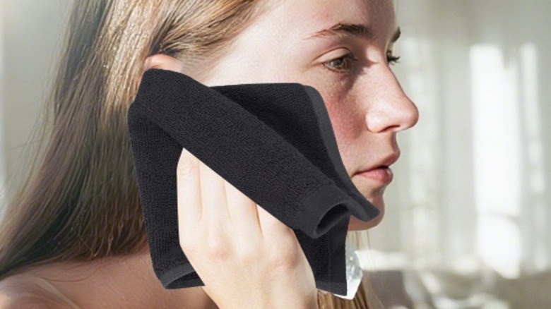 Woman using a black wash cloth to wipe her face