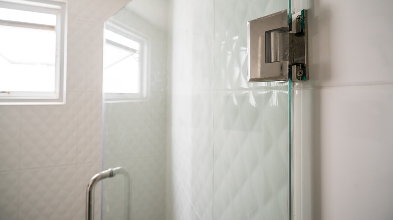 closeup on open glass shower door on hinges