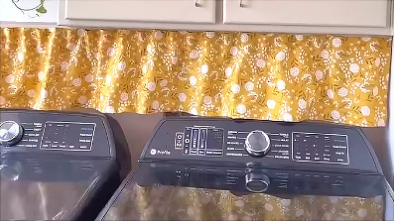 Yellow floral half curtain above washer and dryer