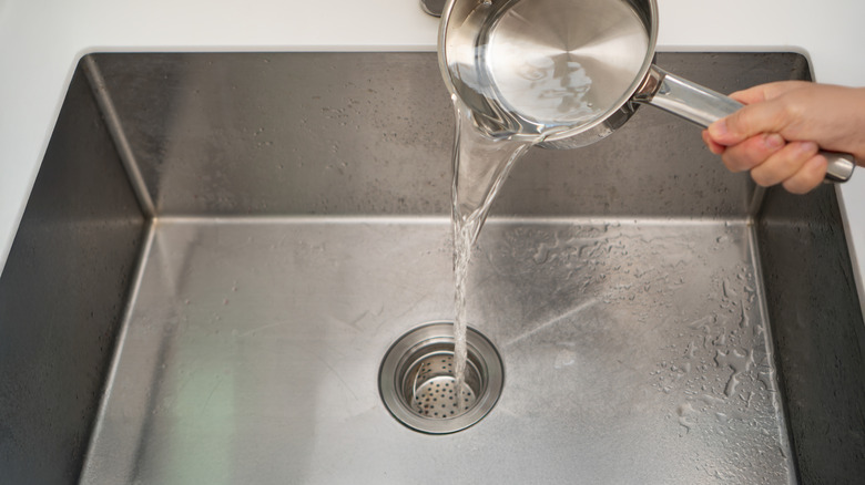 Pouring boiling water down sink