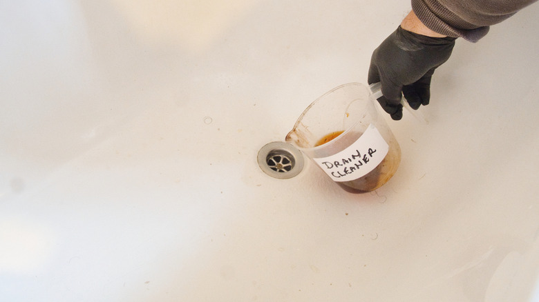 Pouring drain cleaner down drain in bath