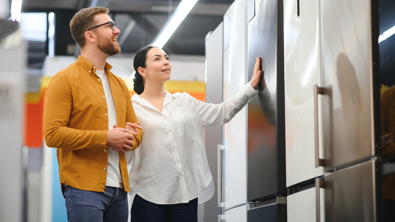 a smiling happy couple shopping for fridges