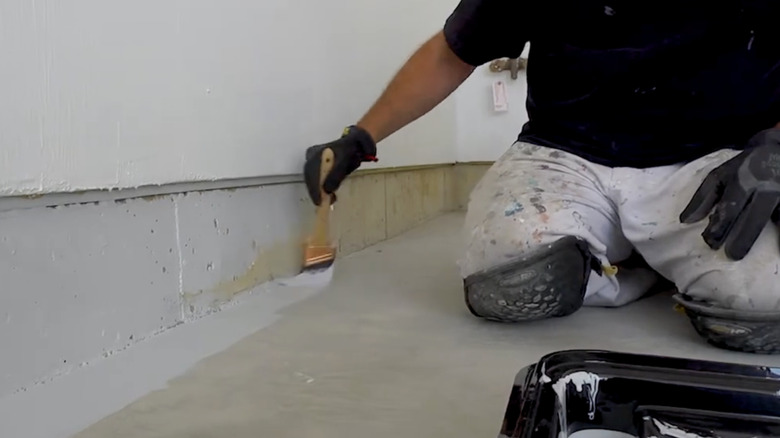 A person applies an H&C concrete coating product to a garage