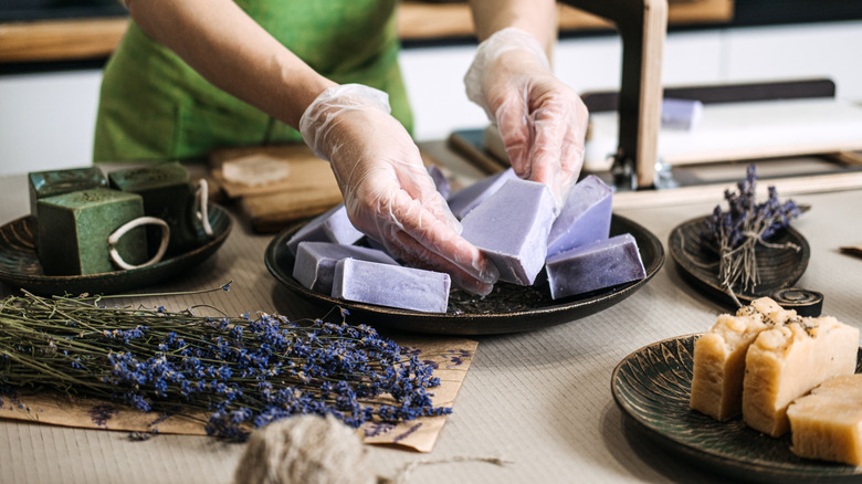 A person forms lavender soap bars with gloved hands.
