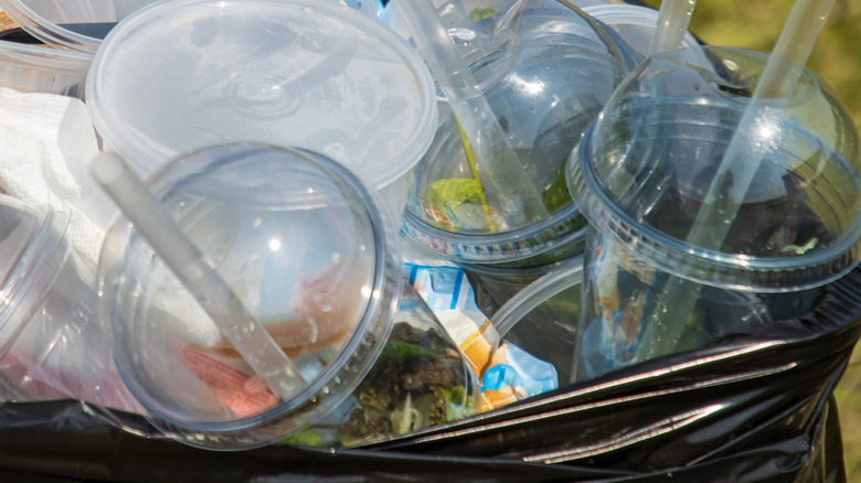 A garbage can overflows with empty plastic beverage containers