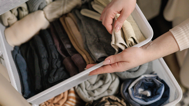 Person organizing items in a set of plastic drawers