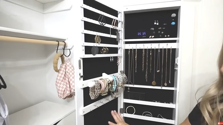 Person showing the inside of a storage mirror with various jewelry pieces being neatly stored