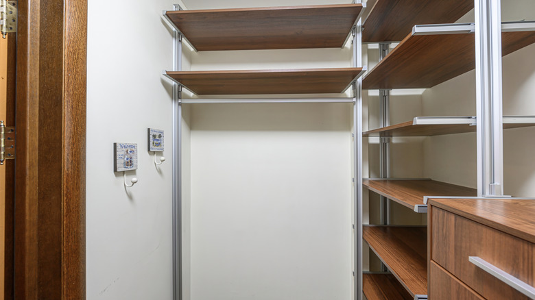Two white hooks installed on the wall inside a closet with built-in shelves