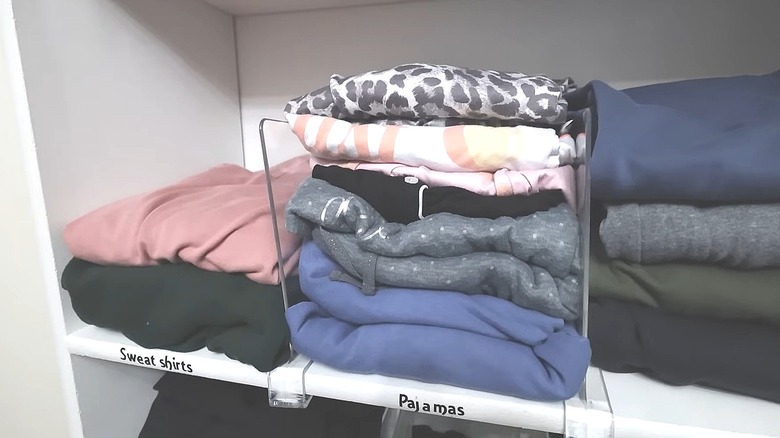 Closet shelf with clear acrylic dividers keeping stacks of clothes neat