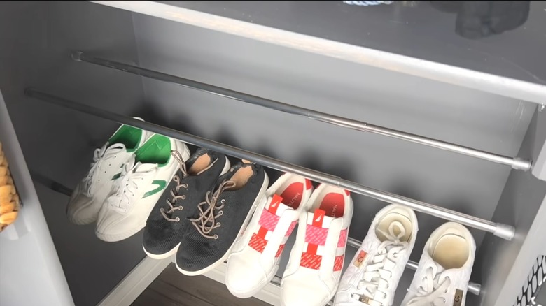 DIY shoe rack made with tension rods with another rack below holding four pairs of shoes