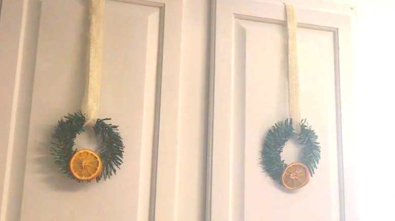 Small green wreaths with dried orange slices on white cabinets