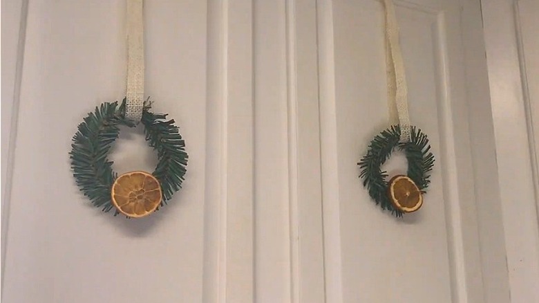 Small green wreaths with dried orange slices on white cabinets