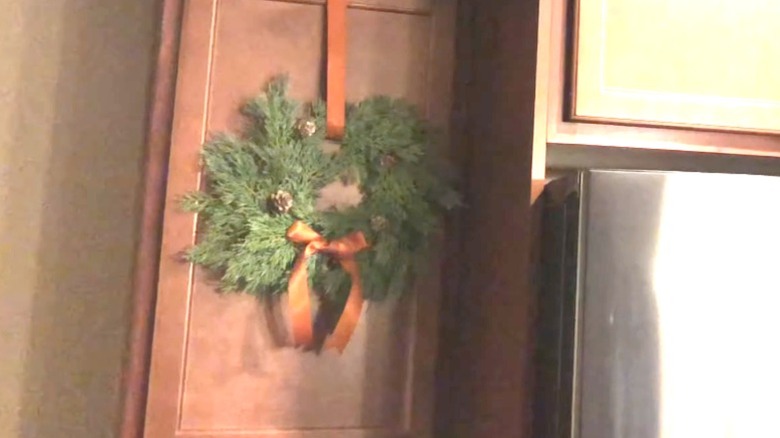 Simple green wreath hanging on wood cabinet with copper ribbon