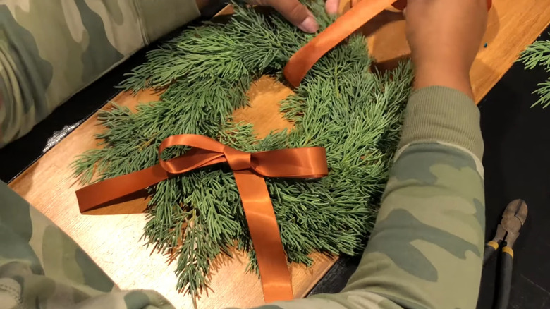 Simple green wreath hanging on wood cabinet with copper ribbon