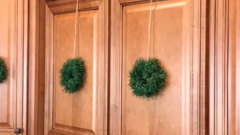 Simple mini green wreaths hanging on light wood cabinets