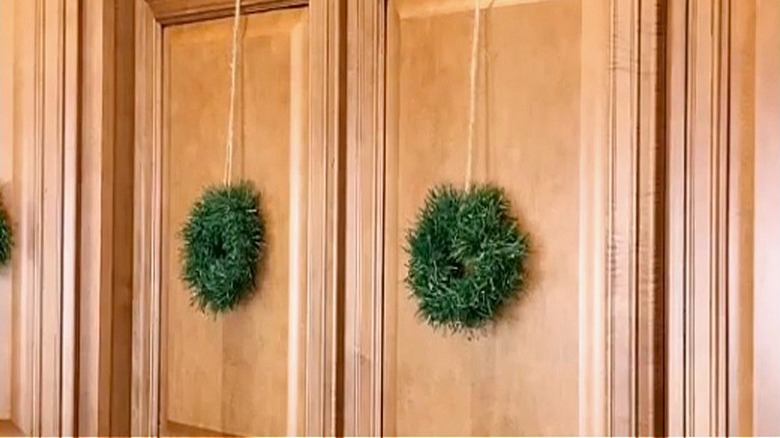 Simple mini green wreaths hanging on light wood cabinets
