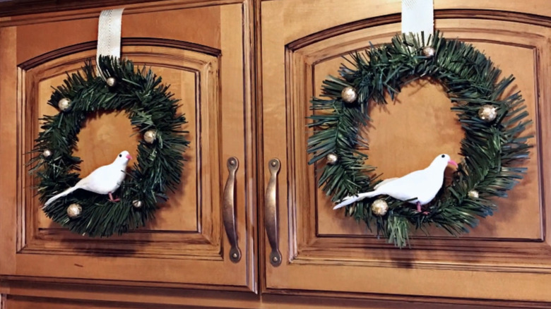 Green wreaths with white doves and gold bells on wood cabinets