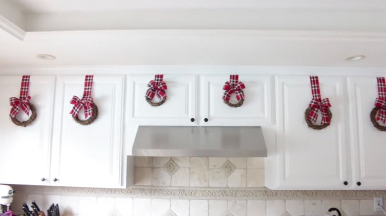 White cabinets decorated with red plaid ribbon wreaths