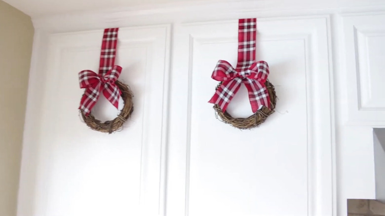 White cabinets decorated with red plaid ribbon wreaths