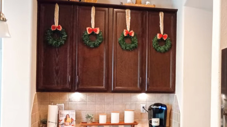 Dark wood kitchen cabinets with hanging holiday wreaths.