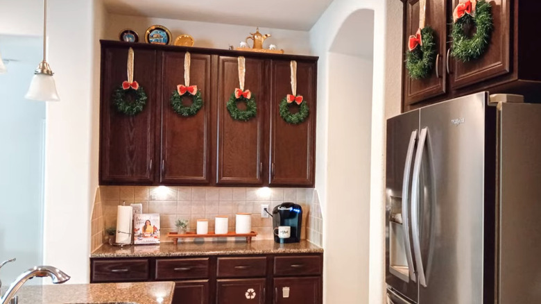 Dark wood kitchen cabinets with hanging holiday wreaths.