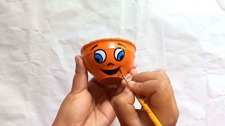 And orange face painted on a teacup