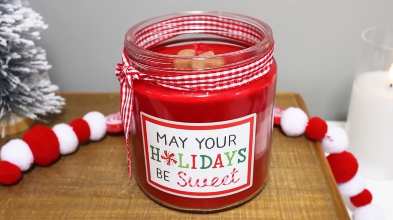 A homemade candle in a jar with a gingerbread man decoration on top