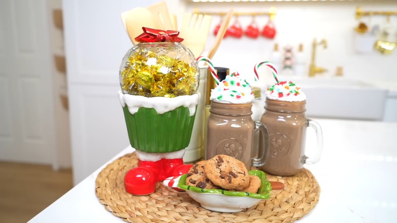 Two imitation hot chocolate jars with a jar of candies and cookies on a dish