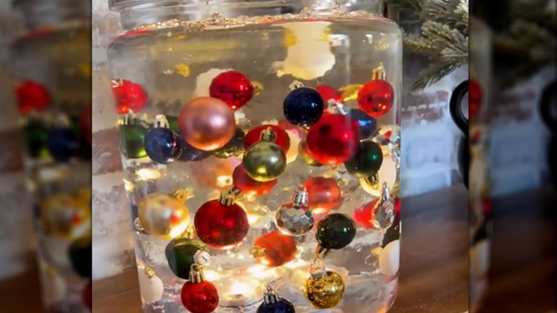 Holiday ornaments floating around in a lit-up jar