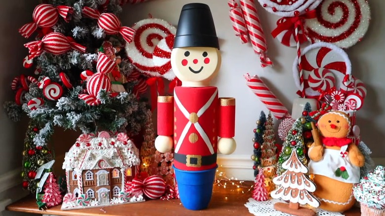 A large toy soldier decor piece surrounded by other holiday decorations on a table