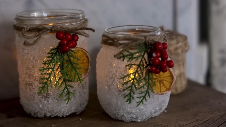 Snowy jar lanterns with decorative wreaths on a table