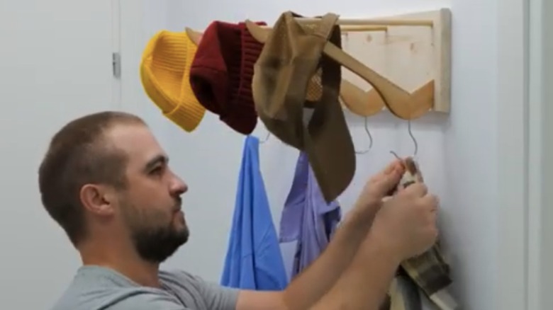 DIY coat and hat rack made from wood scraps and wooden hangers is shown