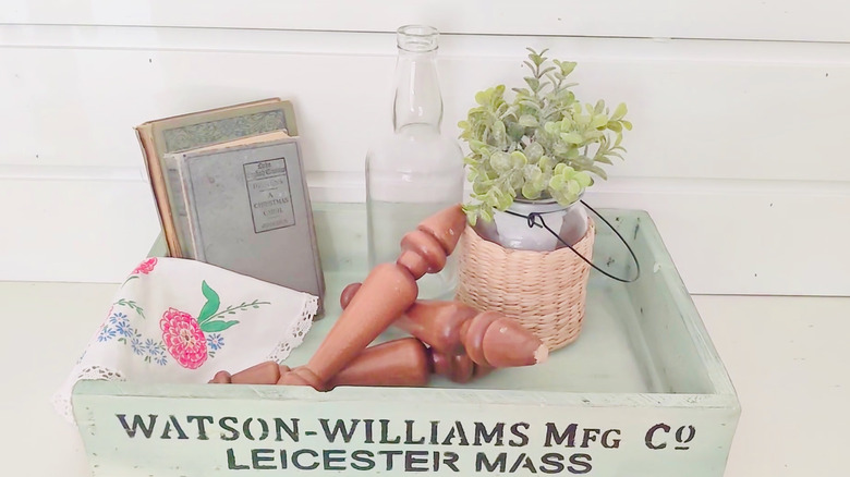 A DIY sage green tray made from wood scraps is filled with decorative items