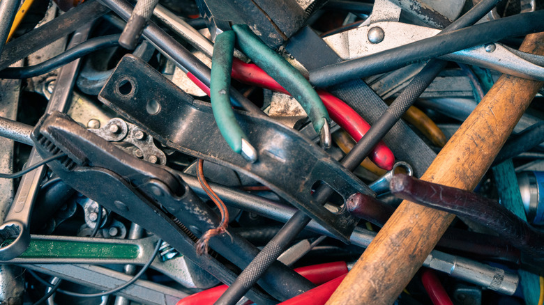 Messy pile of organized tools, including pliers, wrenches, and a hammer
