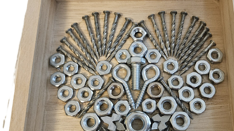 Nuts, screws, and bolts used to form a heart on a piece of wood