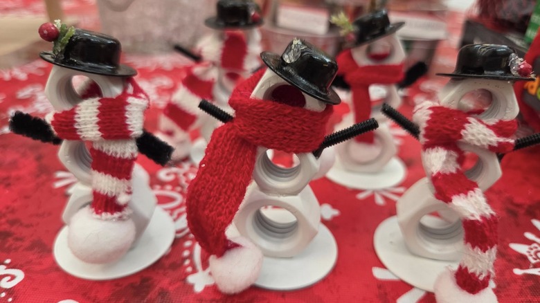 Three snowmen with red and white scarves made from nuts and bolts