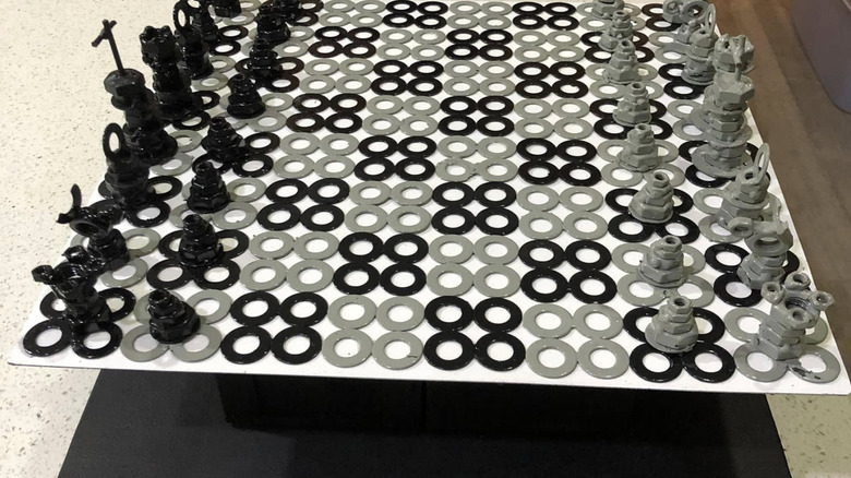 Closeup of a chess set made with washers, nuts, bolts, and and other hardware on a board of black and white washers