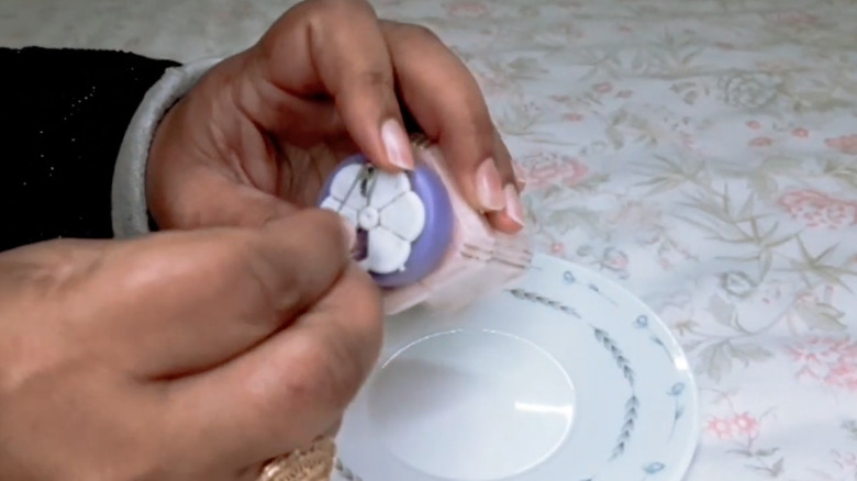 Someone unclogging a spice container with a safety pin