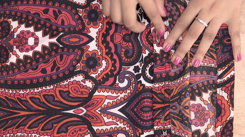 Someone putting a safety pin on the hem of dress