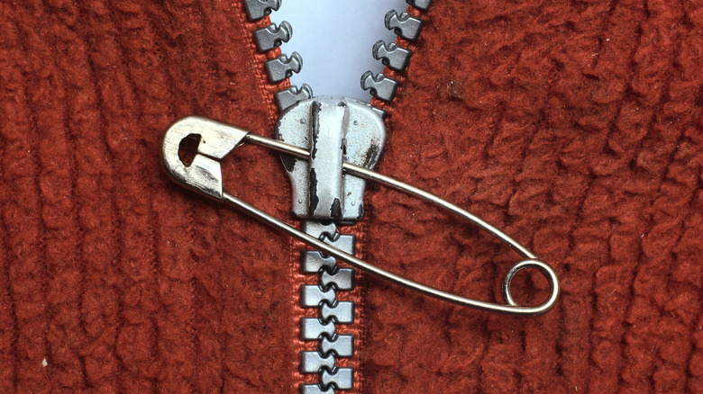 Safety pin on zipper of a brown jacket