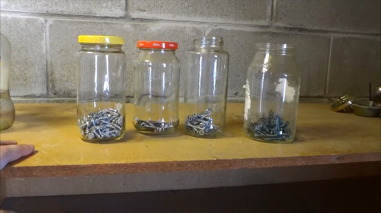 Old jars repurposed as small hardware storage containers.