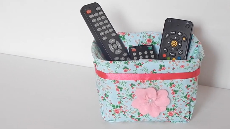 Upcycled ice cream tub covered in fabric for TV remote storage.
