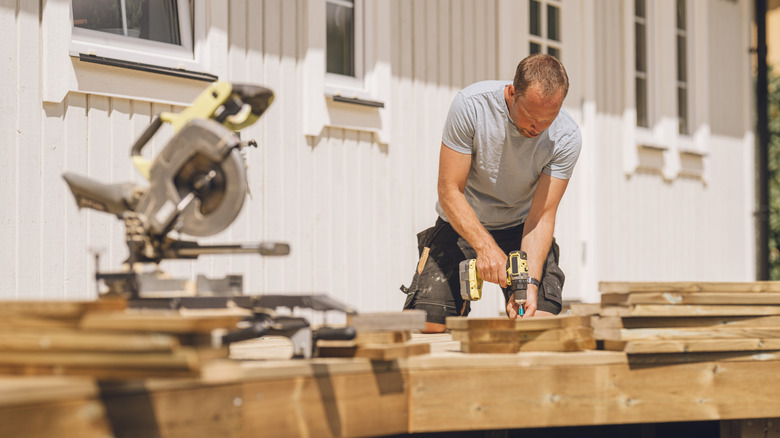 Man building a wooden patio deck outdoors in his garden